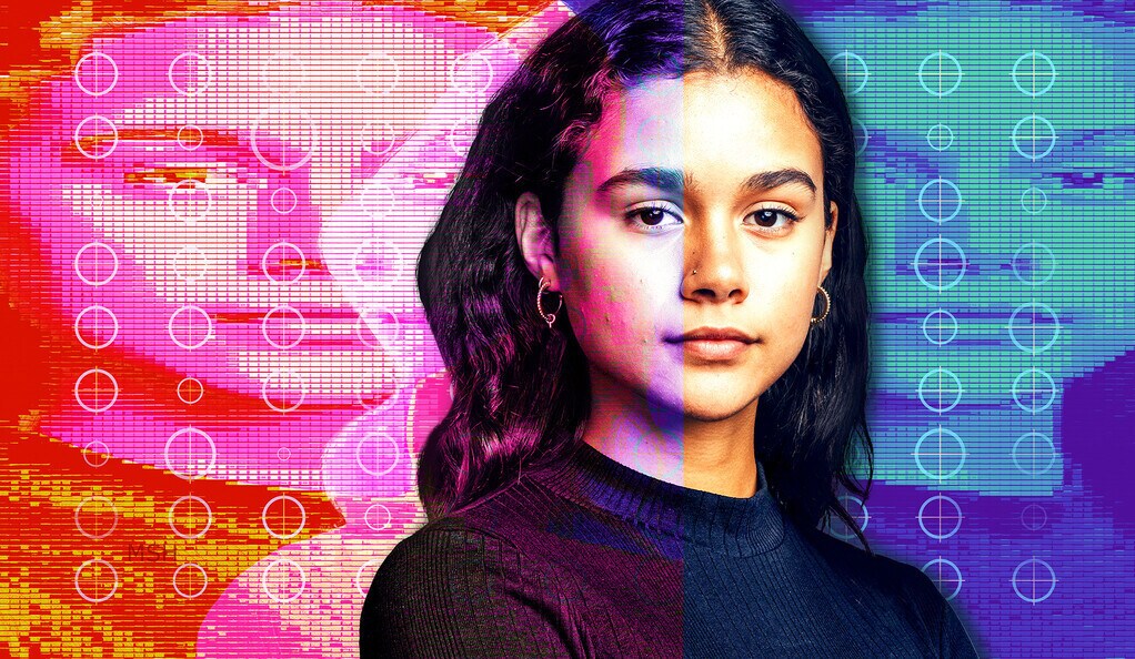 Portrait of young woman looking at camera. Woman sitting with her arms crossed against a grey background.