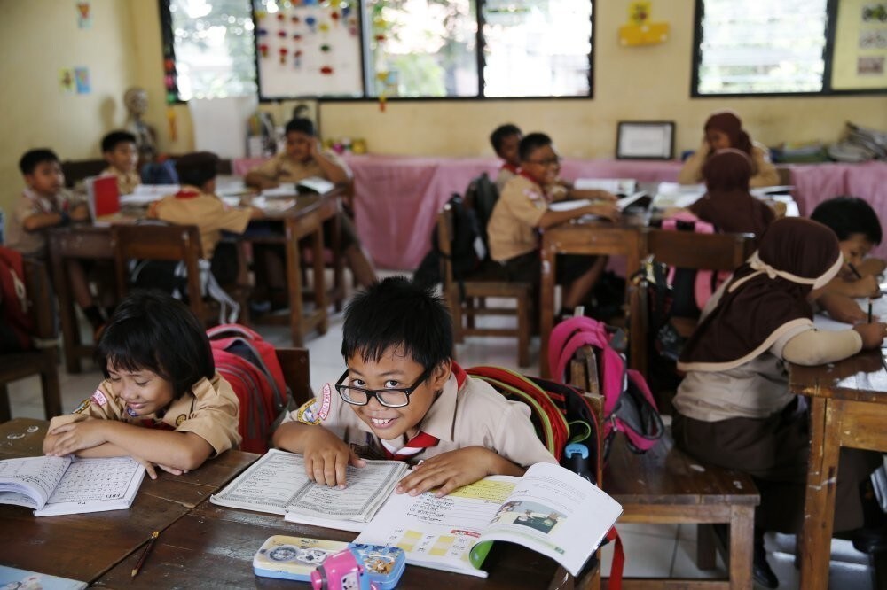A student reacts to the camera as a teacher teaches in Jakarta, Indonesia.