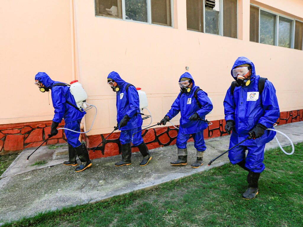 Health workers wearing protective suits spray disinfectant outside of a building during an awareness campaign for coronavirus disease (COVID-19), in Jalalabad, Afghanistan March 19, 2020. REUTERS/Parwiz - RC2UMF9ZSPFY