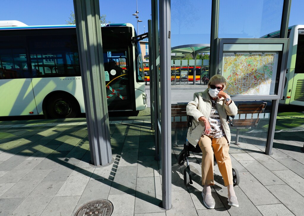 An elderly woman with a protective mask sits at a bus-stop, as the spread of the coronavirus disease (COVID-19) continues in Hanau, Germany, April 20, 2020. REUTERS/Ralph Orlowski - UP1EG4K0QX01M