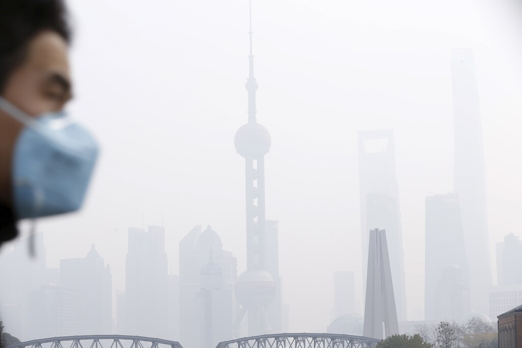 A man wearing a face mask walks on a bridge in front of the financial district of Pudong amid heavy smog in Shanghai, China, December 15, 2015. REUTERS/Aly Song - GF10000265989