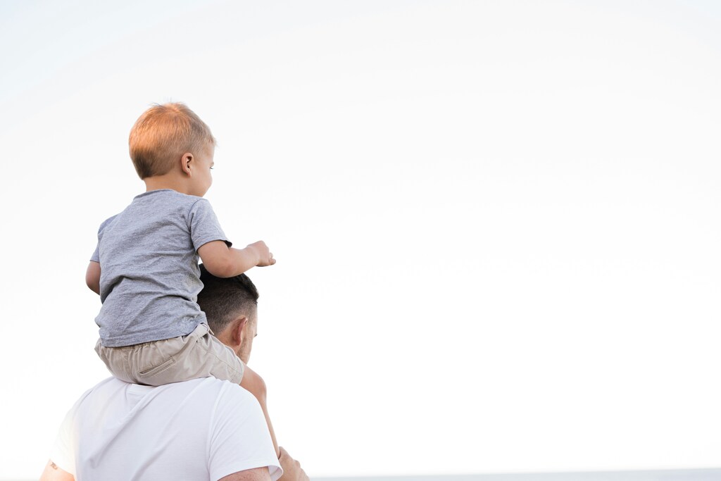A man with a child on his shoulders, illustrating care
