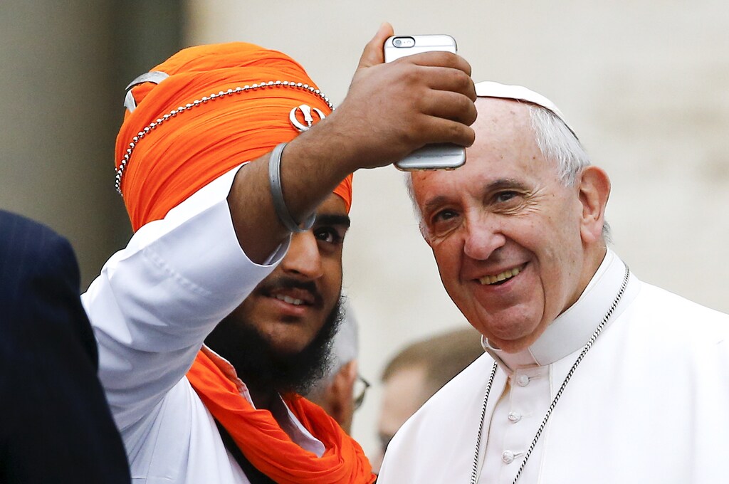 Pope Francis poses for a selfie with a member of the inter-religious community during the weekly audience in Saint Peter's Square at the Vatican October 28, 2015. REUTERS/Stefano Rellandini - RTX1TLBL