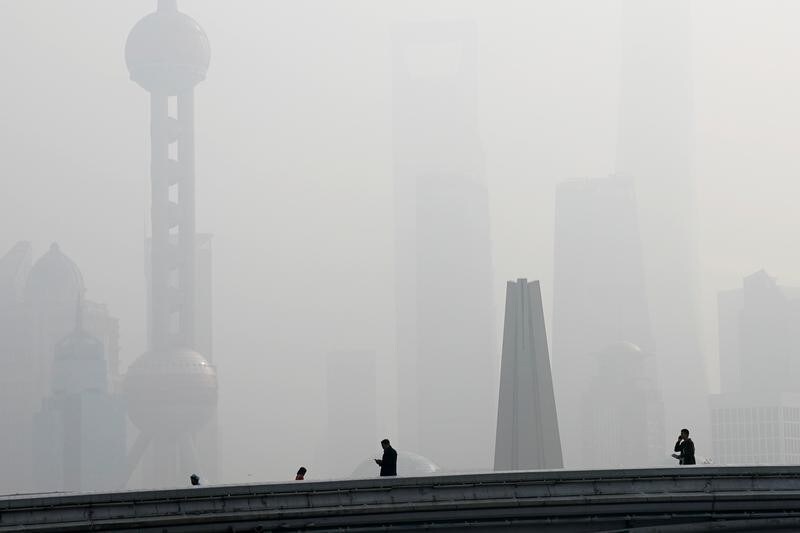 People walk on a bridge in front of the financial district of Pudong, which is covered in smog, during a polluted day in Shanghai, China November 28, 2018. REUTERS/Aly Song TPX IMAGES OF THE DAY - RC1D4A8F7BB0