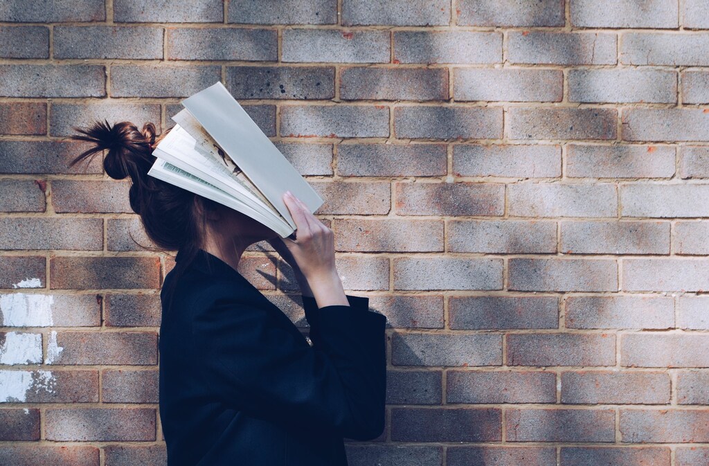 A frustrated student holding a book to her face