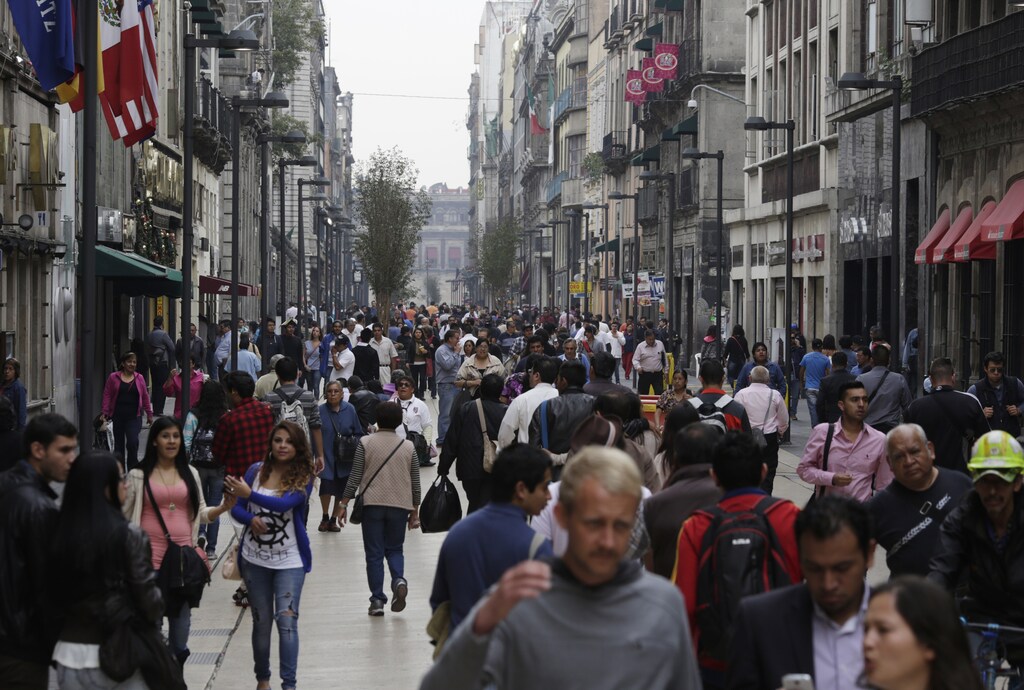 People walk along one of the main streets in downtown Mexico City November 21, 2014. Mexico's finance ministry cut its 2014 growth forecast on Friday after the economy grew unexpectedly slowly in the third quarter in a modest recovery that is now also threatened by rising social unrest. The weak data is the latest blow to President Enrique Pena Nieto, who faces rising protests over the apparent massacre of 43 trainee teachers as well as a conflict-of-interest scandal over a lucrative rail contract. REUTERS/Carlos Jasso (MEXICO - Tags: POLITICS BUSINESS) - RTR4F3UF