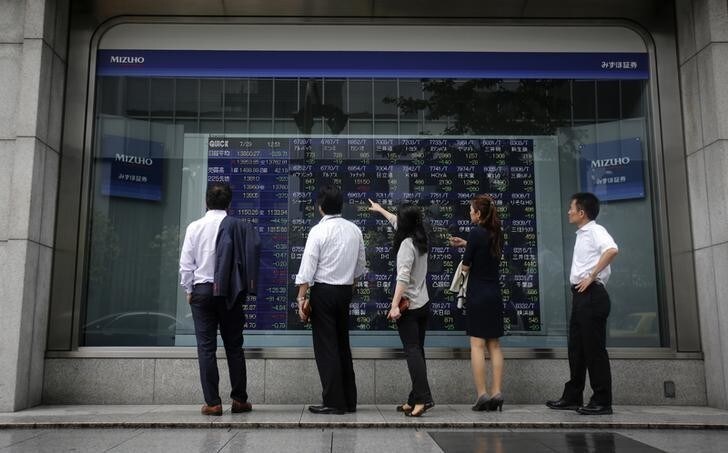 Pedestrians stand in front of a stock quotation board displaying various stock prices outside a brokerage in Tokyo July 29, 2013. Japan's Nikkei share average is expected to fall for the fourth day in a row on Monday as the yen rose against the dollar, while caution over corporate earnings is likely to keep investors on the sidelines. REUTERS/Yuya Shino (JAPAN - Tags: BUSINESS)