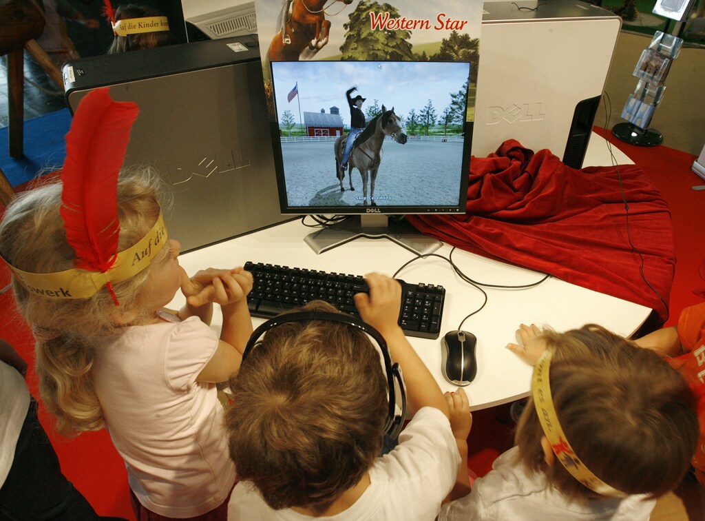 Children play with a computer at an exhibition stand of a German company distributing computer games for children at the Games Convention 2007 fair in the eastern German city of Leipzig August 22, 2007. The Games convention, Europe's leading fair for computer games, runs from August 22 to 26. REUTERS/Arnd Wiegmann (GERMANY) - BM2DVZGCMSAA