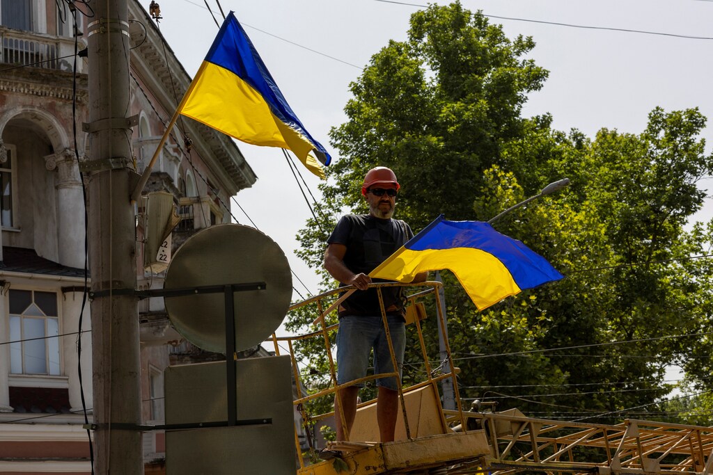 A man puts up Ukrainian national flags on lampposts in Mykolaiv, Ukraine.