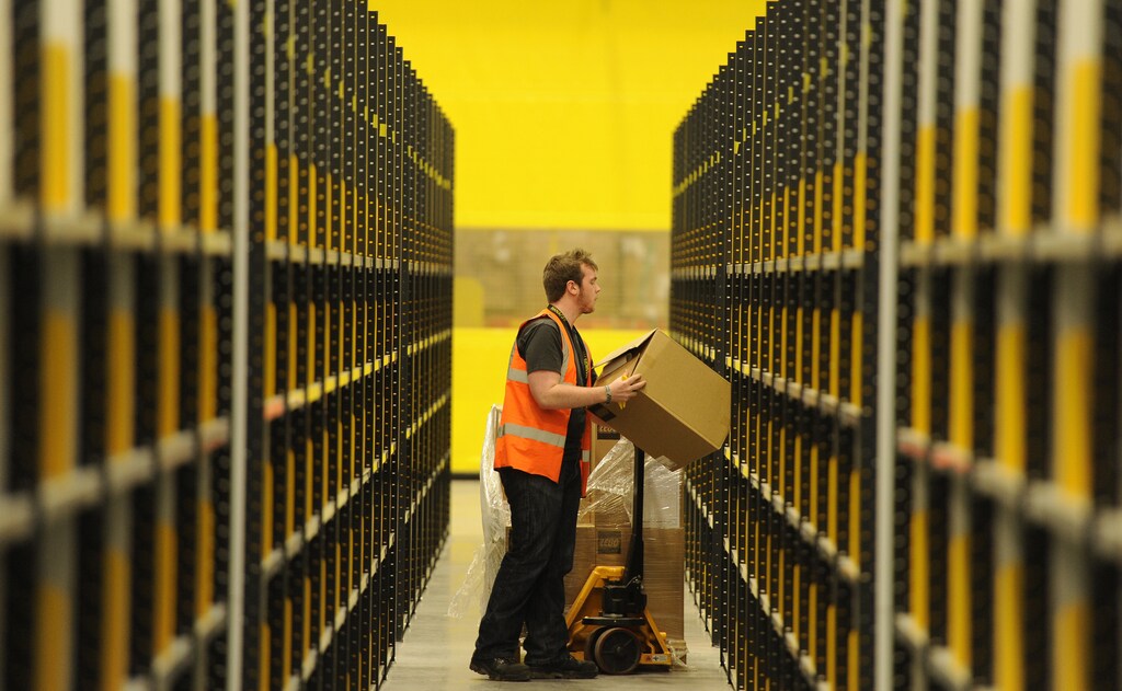 A worker lifts a box at Amazon's new fulfilment centre after it was opened by Scotland's First Minister Alex Salmond in Dunfermline, Scotland, November 15, 2011.The warehouse covers more than one million square feet (93,000 square metres), about the size of 14 soccer pitches, and is Amazon?s biggest in the United Kingdom. It will create 750 permanent jobs, along with a further 1,500 temporary jobs during peak periods. REUTERS/Russell Cheyne (BRITAIN - Tags: POLITICS BUSINESS) - LM1E7BF17XX01