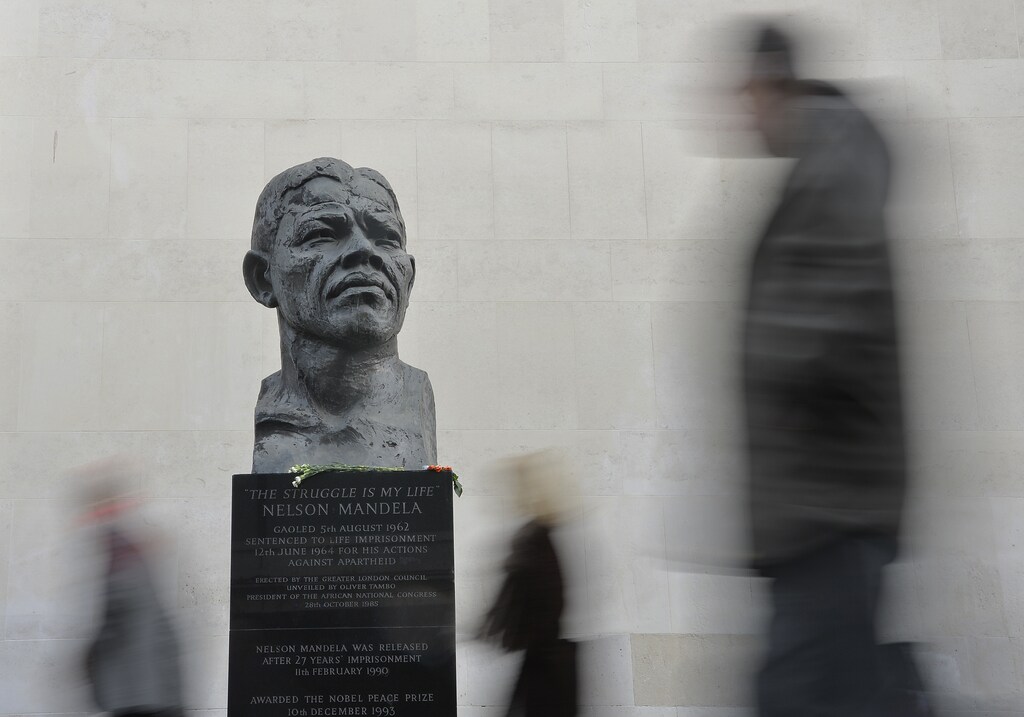 Passers-by look at a statue of former South African President Nelson Mandela on the South Bank in central London December 9, 2013. REUTERS/Toby Melville