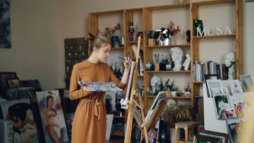 パレットを手にイーゼルに向かって絵を描く女性。ラトビアでは、若者が実用的な職業よりも情熱を注ぐことのできるキャリアを選択しています。