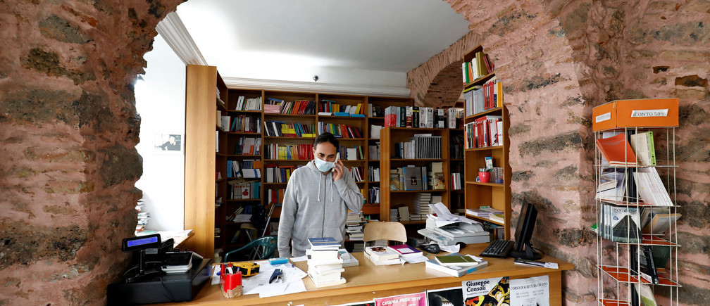 Un vendedor con una máscara facial se encuentra en una tienda mientras el gobierno italiano permite la reapertura de algunas tiendas mientras continúa el cierre nacional, tras el brote de la enfermedad coronavirus (COVID-19) en Catania, Italia, el 14 de abril de 2020.