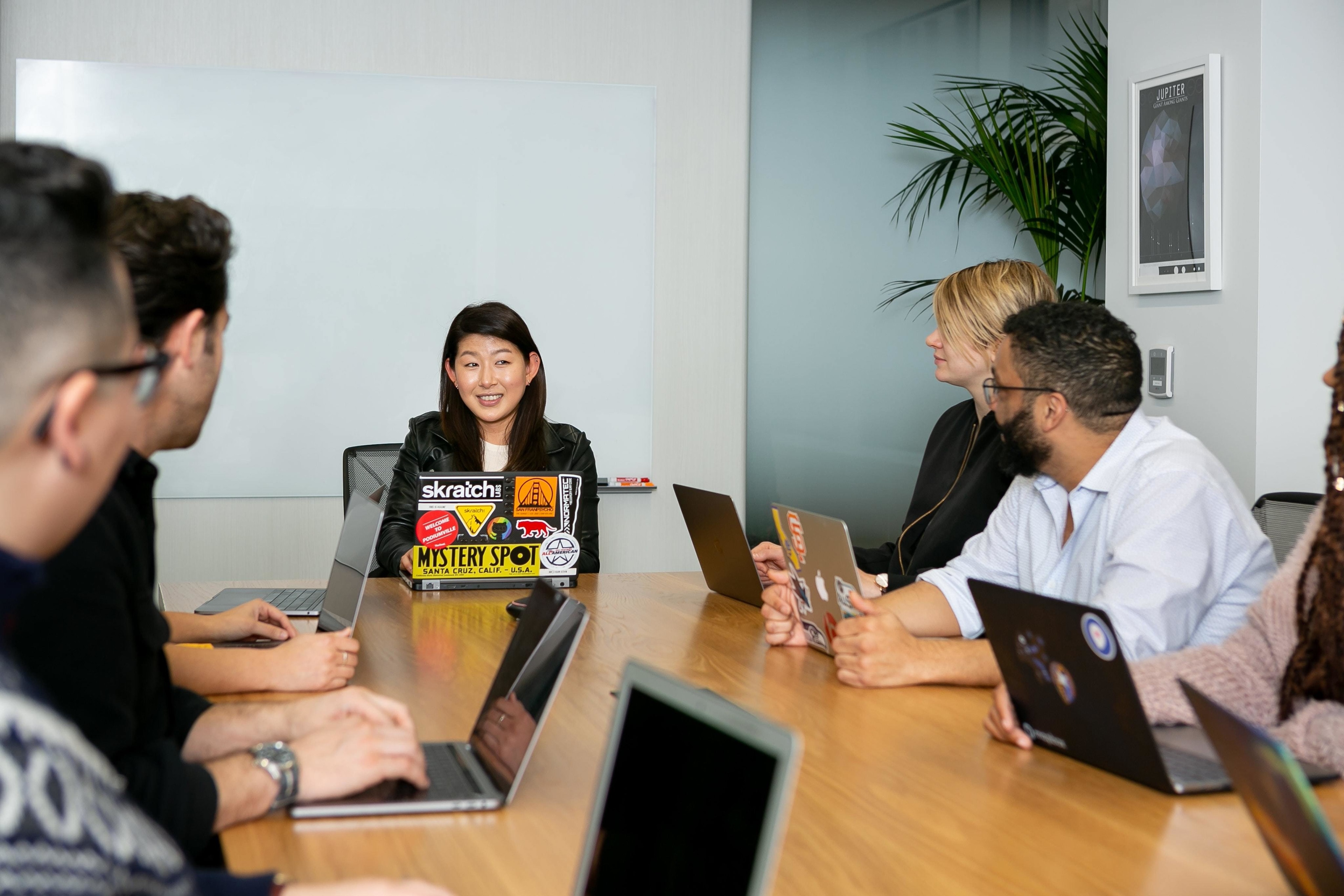 Women entrepreneurs and other in a meeting room with laptops.