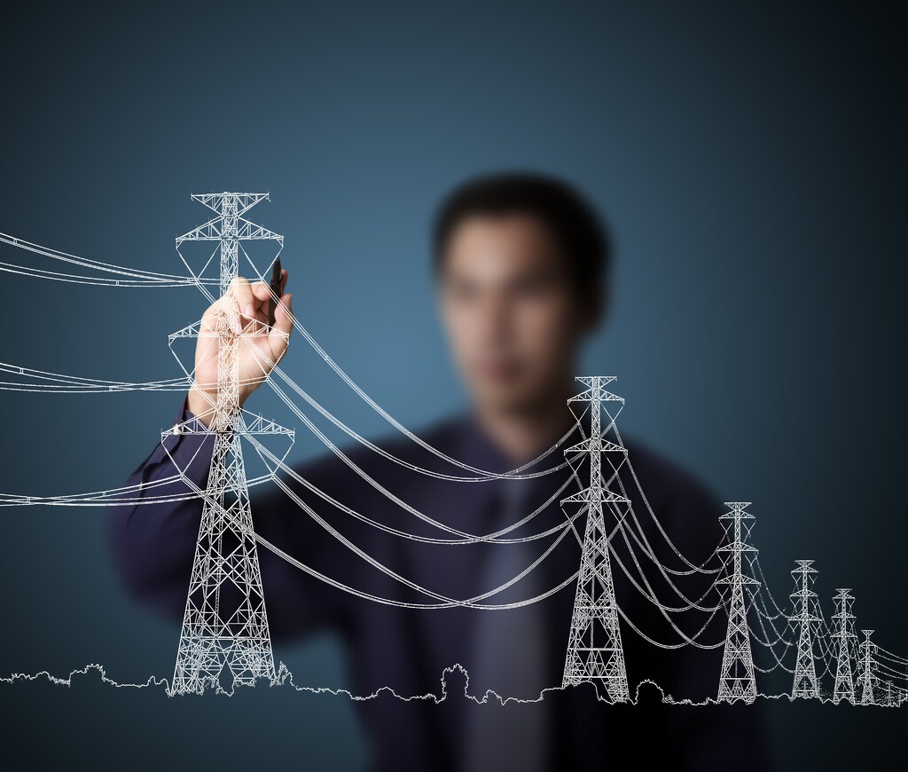 man in shirt and tie drawing industrial electric pylon and wire; energy integration