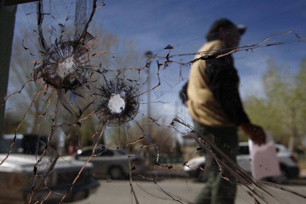 A person walks past a glass door damaged by bullets at the police headquarters where Marisol Valles Garcia used to work as the police chief, in Praxedis G. Guerrero March 7, 2011. The 20-year-old female student who became the police chief in one of Mexico's most dangerous drug war towns was fired by the mayor on Monday for not showing up to work after Mexican media reported she received death threats. Marisol Valles, a criminology student in Mexico's violent city of Ciudad Juarez, took charge of the police force in the neighboring municipality of Praxedis G. Guerrero near El Paso, Texas in October, sparking intense media attention after few candidates dared to apply for the dangerous job. REUTERS/Gael Gonzalez (MEXICO - Tags: POLITICS CRIME LAW SOCIETY) - GM1E7380AXX01