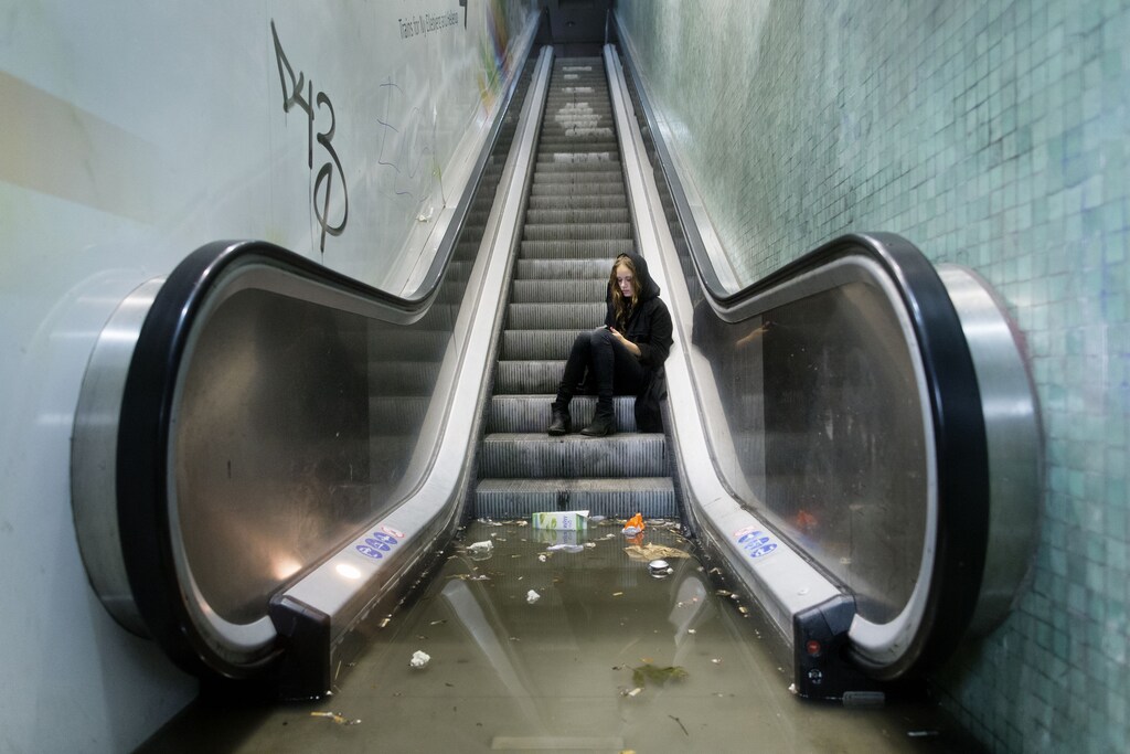 A woman calls for assistance after being trapped by water at a flooded train station during a heavy rainstorm in Copenhagen.