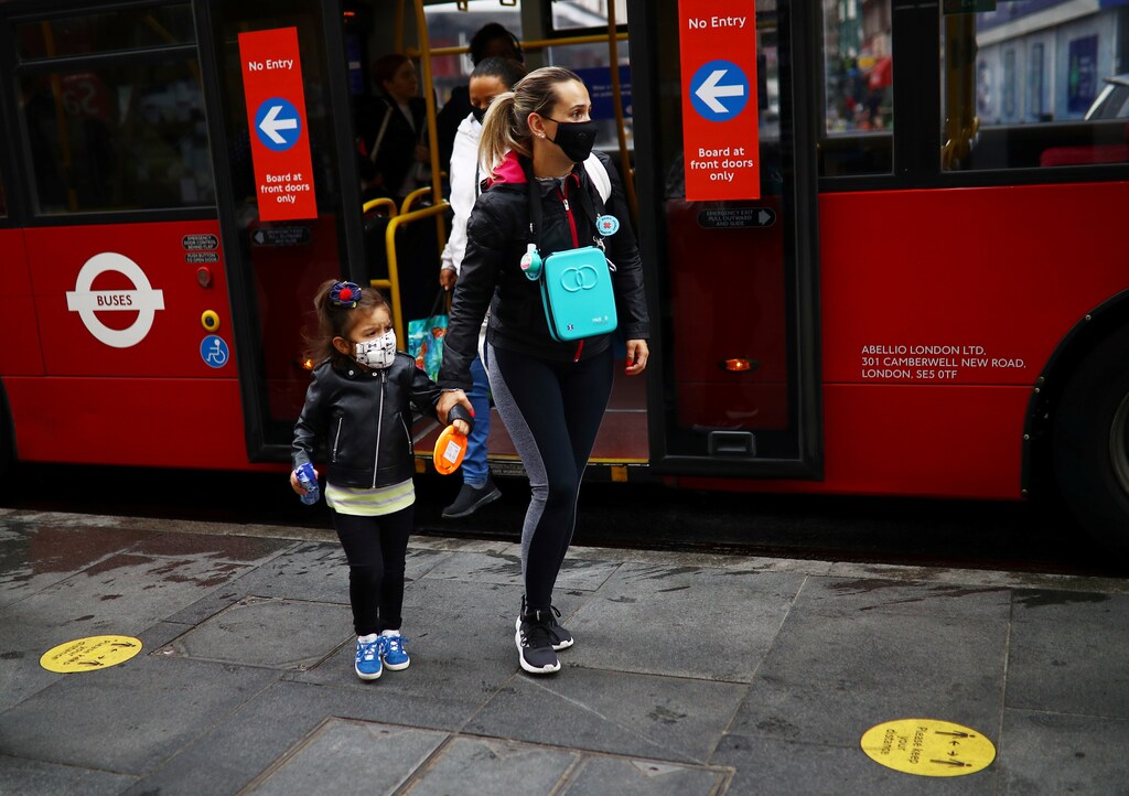 A woman and a child are seen wearing a protective face mask by a London bus, following the outbreak of the coronavirus disease (COVID-19), London, Britain, June 10, 2020. REUTERS/Henry Nicholls - RC296H9CA1HE