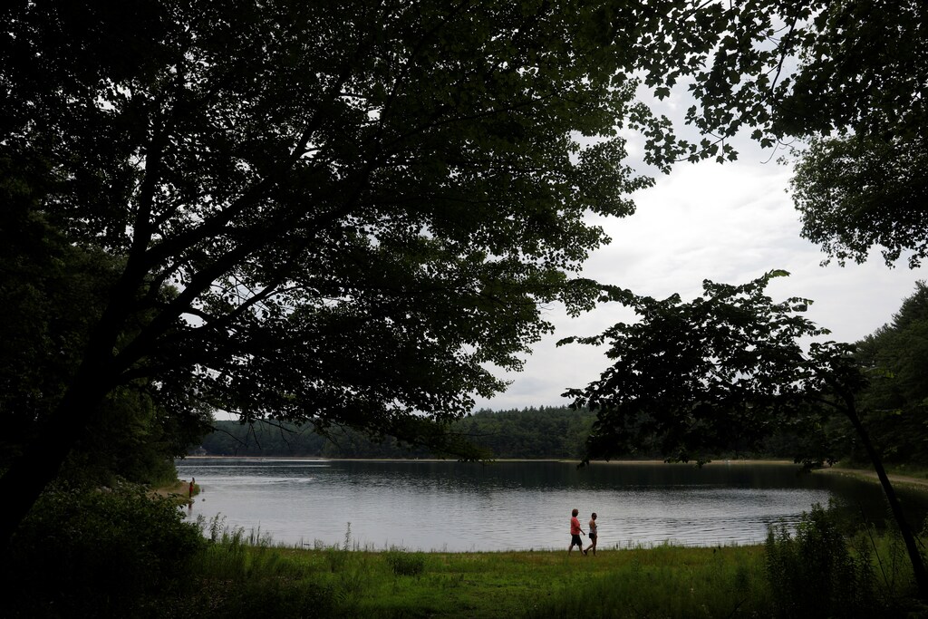 Two women walk along the shore of Walden Pond on what would have been the 200th birthday of Henry David Thoreau, author of the book "Walden," in Concord, Massachusetts, U.S., July 12, 2017. REUTERS/Brian Snyder - RTX3B6N1