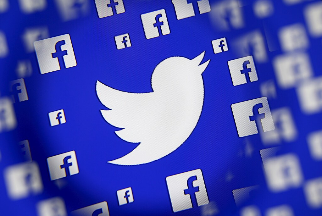 Logo of Twitter and Facebook are seen through magnifier on display in this illustration taken in Sarajevo, Bosnia and Herzegovina. REUTERS/Dado Ruvic