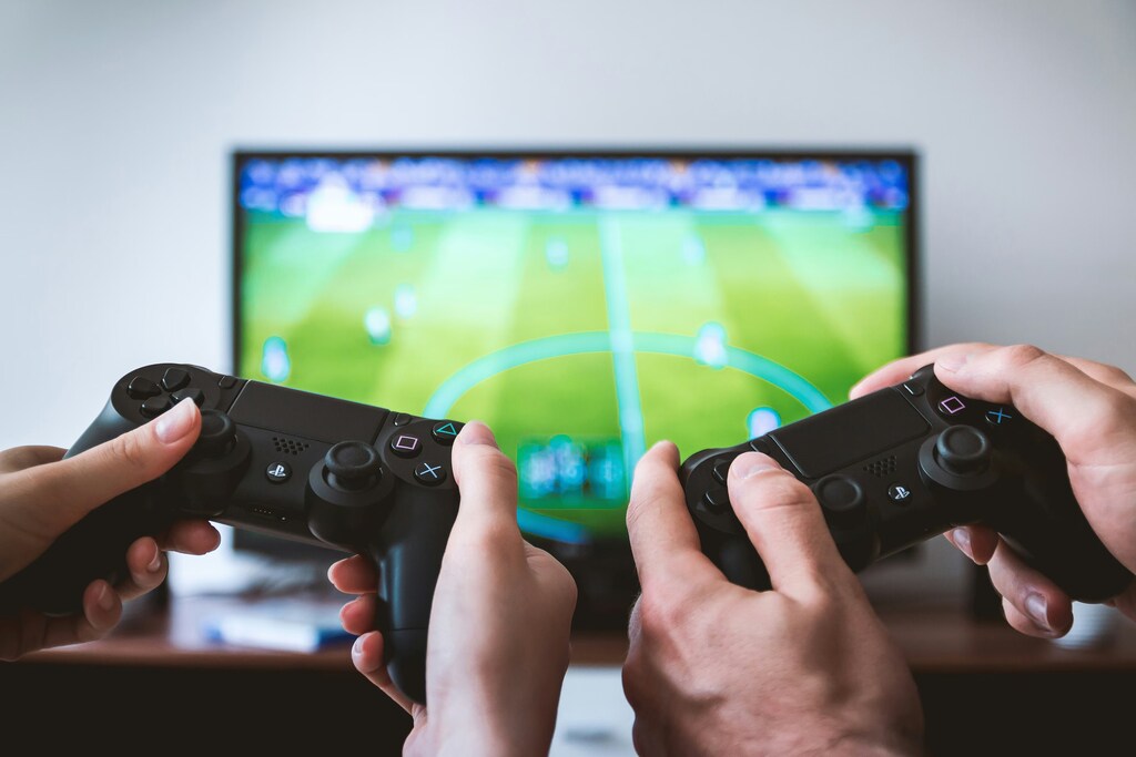 Usuarios utilizando consolas de videojuegos para jugar a un partido de fútbol.