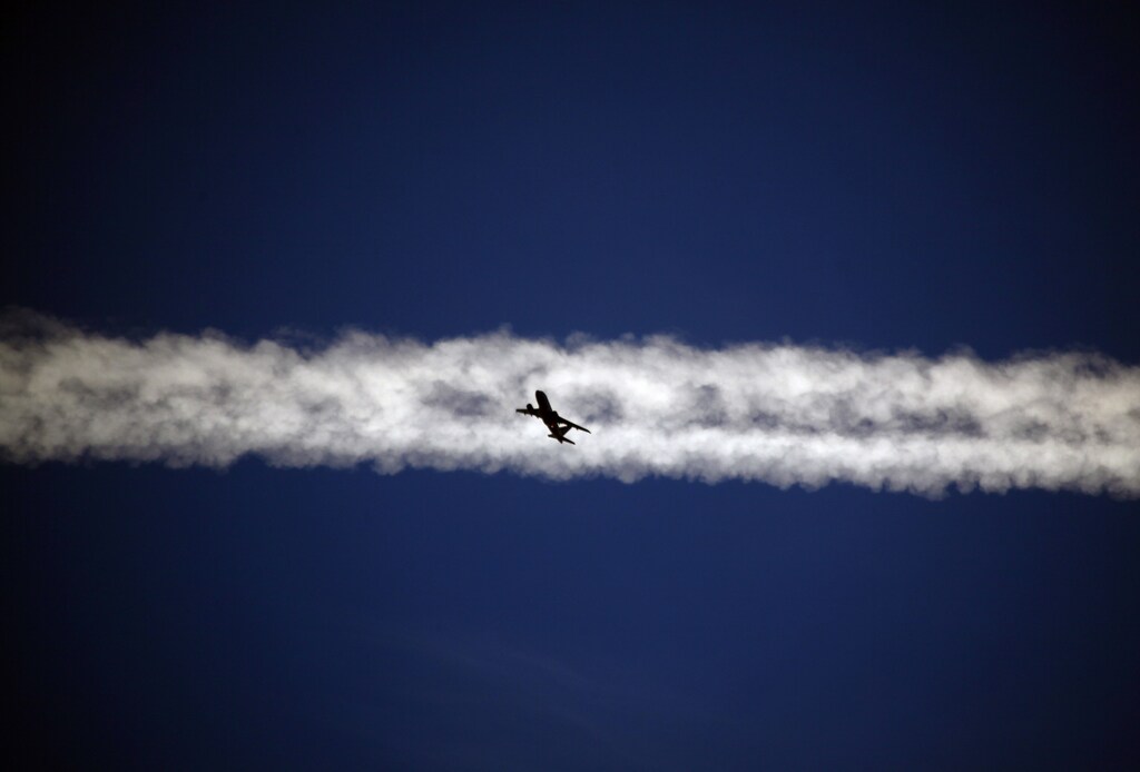 An aeroplane flies underneath the jet stream of another aircraft above the Italian city of Padua.