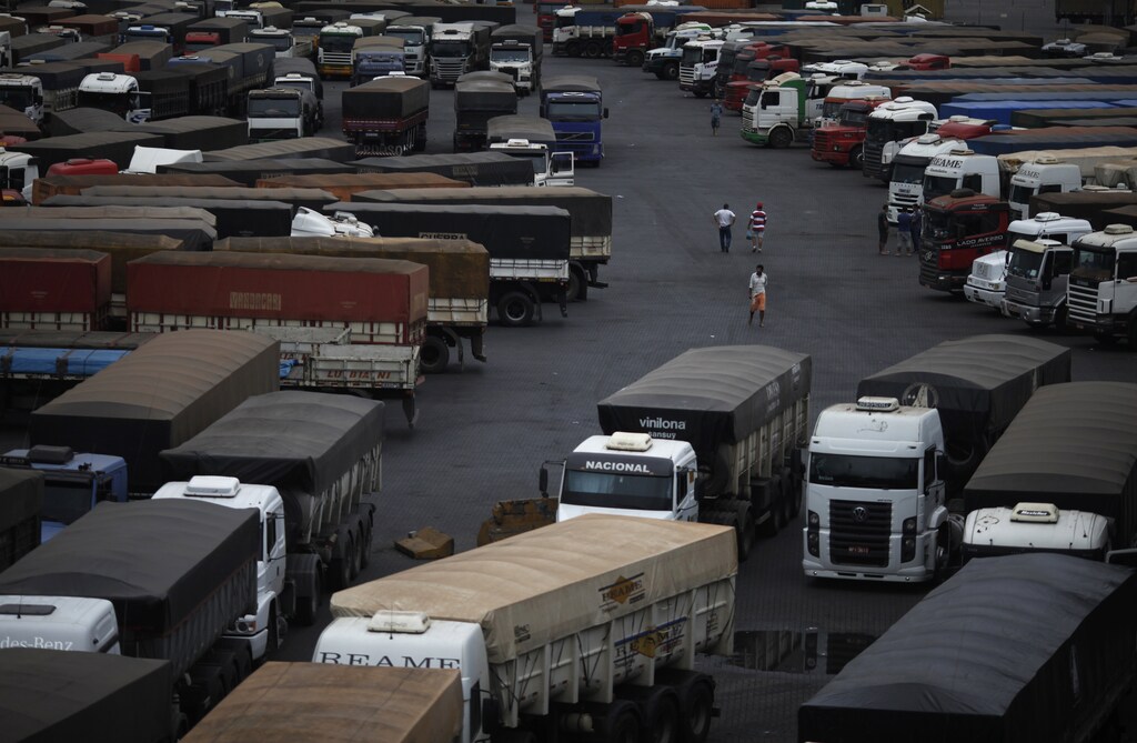 Drivers walk in front of trucks parked as they wait to unload their cereal grain freight at Ecopatio in Cubatao, September 20, 2012.