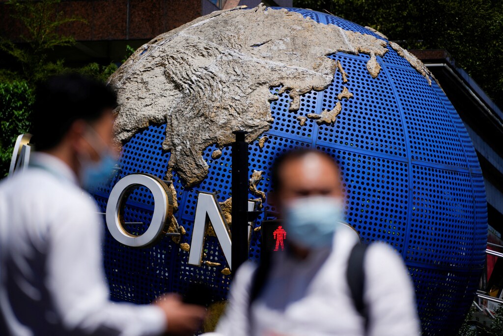 Men wearing face masks following the coronavirus disease (COVID-19) outbreak stand in front of a large globe in Shanghai, China, 4 August 2022.