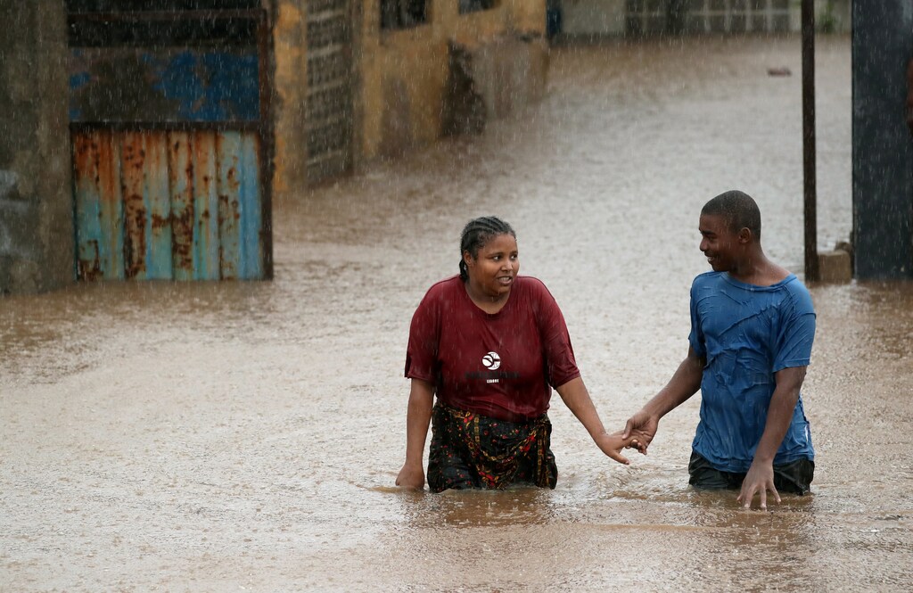 A man helps a woman through a flooded neighbourhood in the aftermath of Cyclone Kenneth, in Pemba, Mozambique, April 28, 2019. REUTERS/Mike Hutchings TPX IMAGES OF THE DAY - RC1672267310