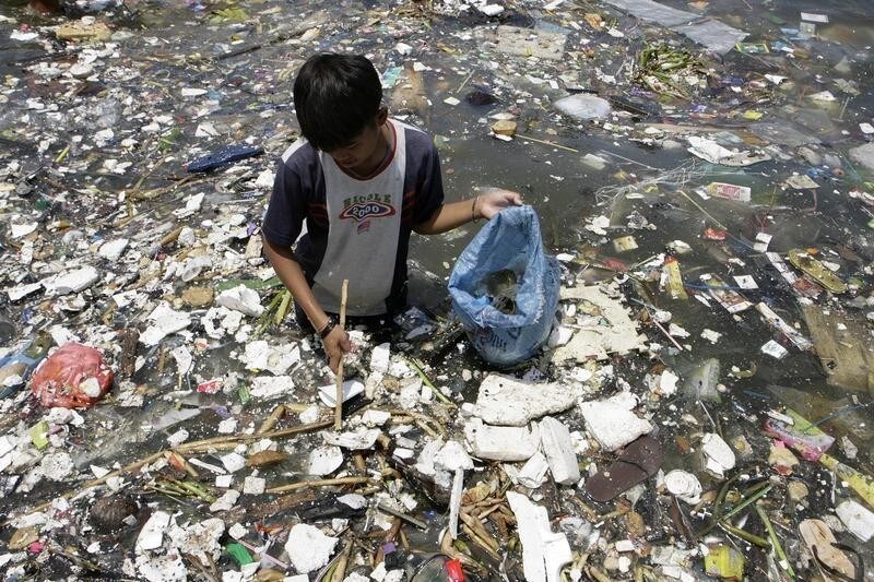 A boy collects plastic materials near a polluted coastline to sell in Manila April 9, 2008. The 4th global conference on oceans, coasts and islands which began on Tuesday is a forum for developing and poor countries, many of which would be worst affected by climate change and nations will discuss how to preserve fisheries, protect coastlines and limit pollution. REUTERS/Cheryl Ravelo (PHILIPPINES) - GM1E449184C01