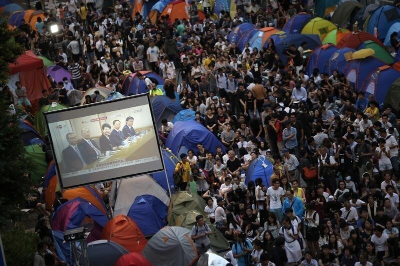 Pro-democracy protesters watch formal talks between student protest leaders and government officials on a video screen near the government headquarters in Hong Kong October 21, 2014. Hong Kong Chief Executive Leung Chun-ying said on Tuesday there was room for the committee that selects candidates for the territory's 2017 election to be made "more democratic." REUTERS/Carlos Barria (CHINA - Tags: CIVIL UNREST POLITICS TPX IMAGES OF THE DAY) - GM1EAAL1O7201
