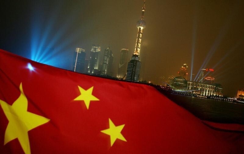 The Chinese flag flies with the Pudong skyline in the background during the Shanghai Cooperation Organisation (SCO) meetings in Shanghai June 14, 2006. [China urged Iran on Wednesday to respond positively to a package of incentives and penalties aimed at persuading it to give up uranium enrichment and defuse a showdown with Washington and its allies.] - PBEAHUNMKBM