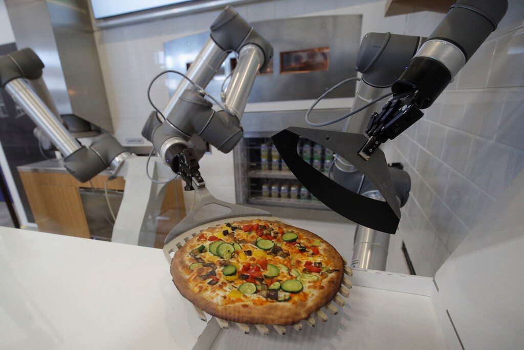 A pizzaiolo robot prepares a pizza before the customers eyes at the showroom of French food startup EKIM in Montevrain near Paris, France, June 26, 2018. Picture taken June 26, 2018. REUTERS/Philippe Wojazer - RC12FDFA79A0