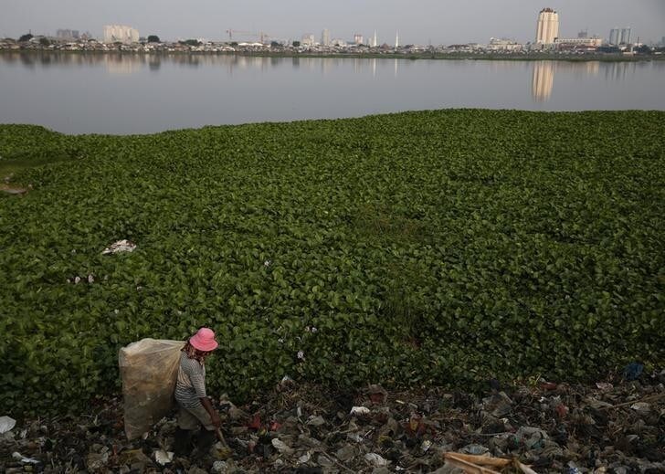 Saidi, a former fisherman, walks as he collects plastic cups for recycling at Pluit lake in Jakarta August 21, 2013. Saidi said that he can collect 20 kilograms of plastic a day and sell that for 14,000 rupiah ($1) per kilogram. REUTERS/Beawiharta (INDONESIA - Tags: SOCIETY POVERTY BUSINESS)