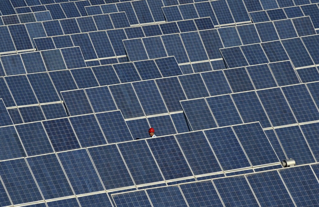An employee walks between rows of solar panels at a solar power plant on the outskirts of Dunhuang, Gansu province June 10, 2011. REUTERS/Stringer (CHINA - Tags: ENERGY ENVIRONMENT SCI TECH) - GM1E76A10N901