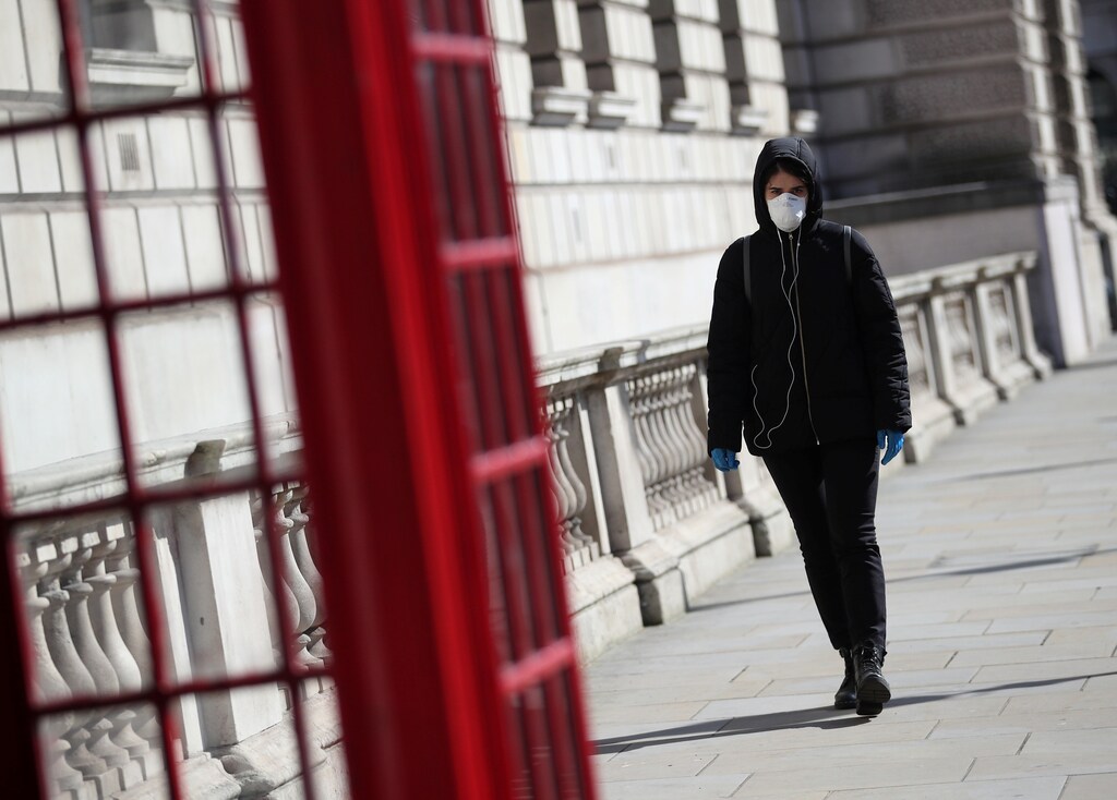 A woman wearing a protective face mask and gloves walks through Westminster as the spread of the coronavirus disease (COVID-19) continues, London, Britain, March 24, 2020. REUTERS/Hannah McKay