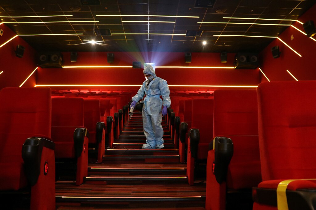 A worker wearing personal protective equipment (PPE) sanitizes seats inside the Inox Leisure movie theatre ahead of its reopening, amidst the outbreak of the coronavirus disease (COVID-19), in Mumbai, India, October 13, 2020. REUTERS/Niharika Kulkarni - RC2NHJ9WXDTJ