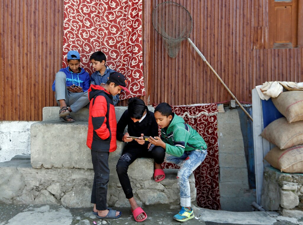 Children play games on their mobile phones in a neighbourhood in Srinagar October 10, 2019. Authorities reopened schools in Indian Kashmir's main city on August 19 but most classrooms were empty as parents kept their children home, fearing unrest over Indian government's decision to revoke the region's autonomy. Picture taken October 10, 2019. REUTERS/Danish Ismail - RC197B3D8380