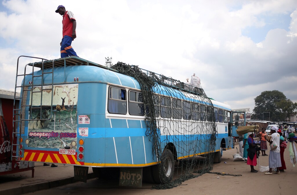 Women chat in front of a bus as a worker waits to load luggage at a bus terminus in Mbare township, outside Harare, Zimbabwe, November 27, 2017. REUTERS/Siphiwe Sibeko - RC1A62BC8A10