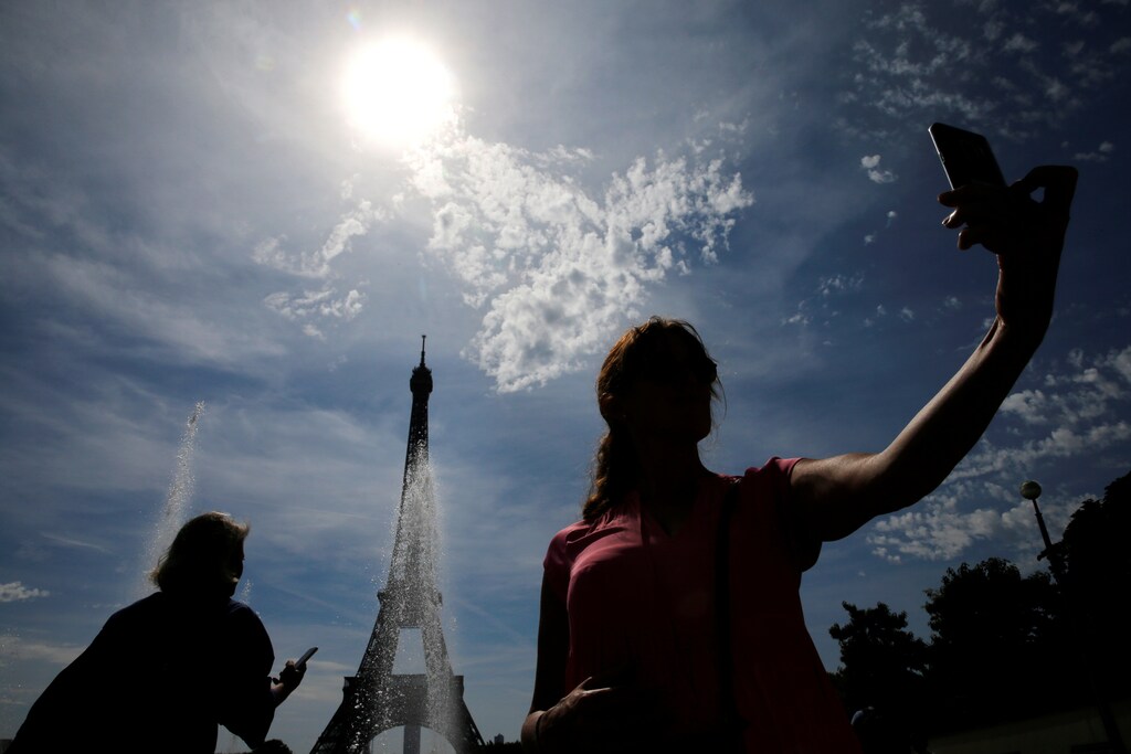 A woman takes a selfie during a sunny and hot day at the Trocadero fountain in front of the Eiffel Tower in Paris, France, August 4, 2019. REUTERS/Pascal Rossignol