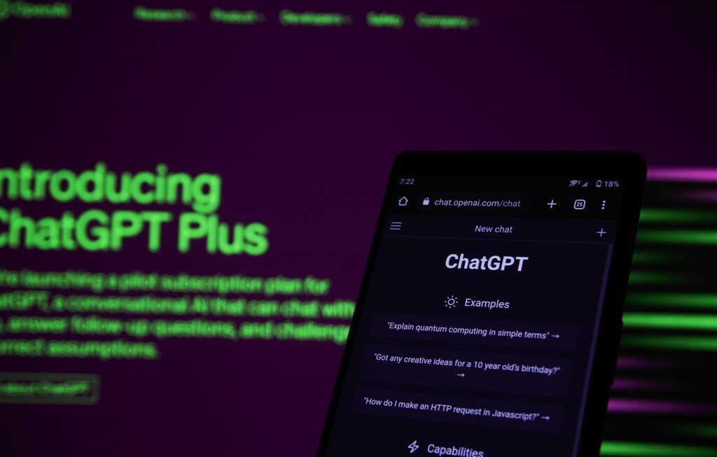 An AI chatbot on a phone with a computer in the background.