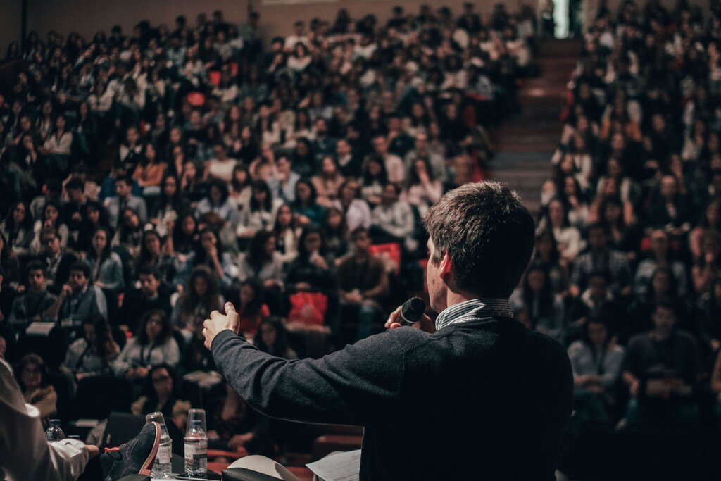 A man talks in front of a crowd.