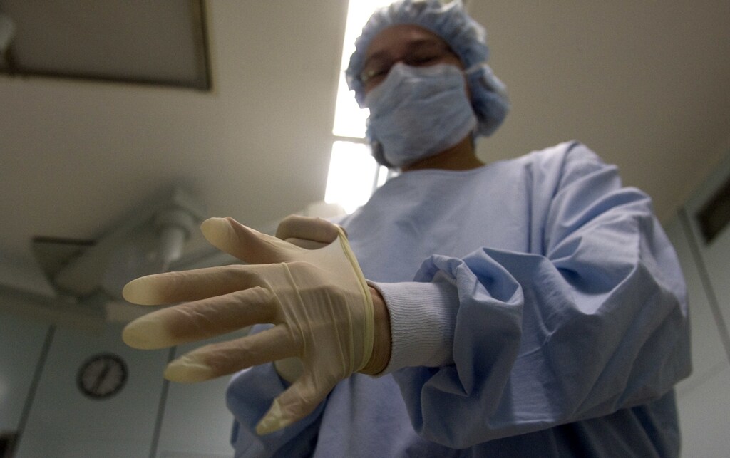 A surgery nurse puts on gloves before procedures on a patient with MRSA (Methicillin resistant Staphylococcus Aureus) in the operating theatre of the Unfallkrankenhaus Berlin (UKB) hospital in Berlin February 29, 2008. REUTERS/Fabrizio Bensch (GERMANY) - RTR1XQJV
