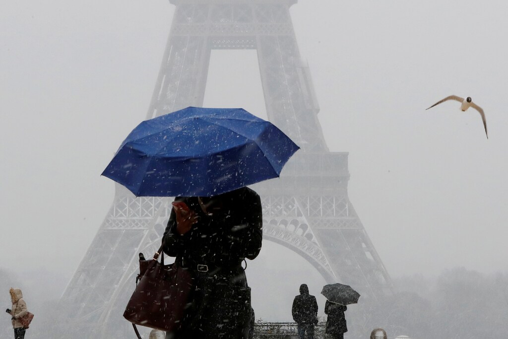 A woman holds an umbrella to protect herself from falling snow near the Eiffel Tower in Paris, as winter weather with snow and freezing temperatures arrive in France, February 6, 2018. REUTERS/Gonzalo Fuentes TPX IMAGES OF THE DAY - RC12BBCF1B40