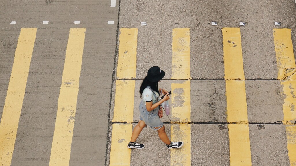 A person crossing the road, whilst on their phone.
