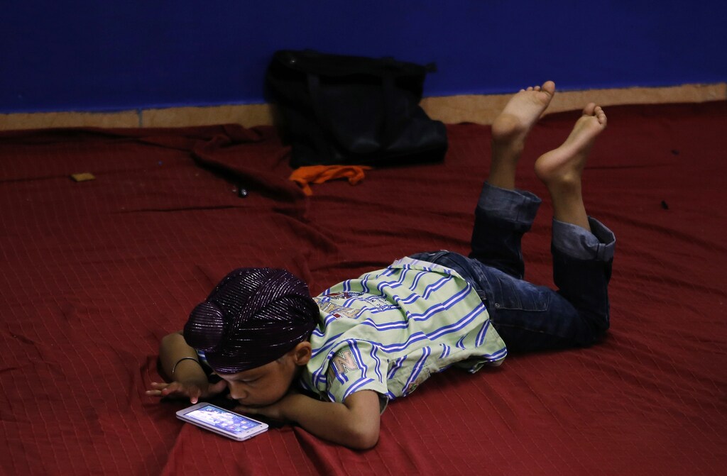 A young Sikh plays with a smartphone inside a Sikh temple during their Baisakhi festival in Palma de Mallorca on the Spanish Balearic island of Mallorca, April 27, 2014. Sikhs celebrate Baisakhi, a harvest festival, as the beginning of the New Year. REUTERS/Enrique Calvo (SPAIN - Tags: RELIGION SOCIETY) - GM1EA4S01Z201