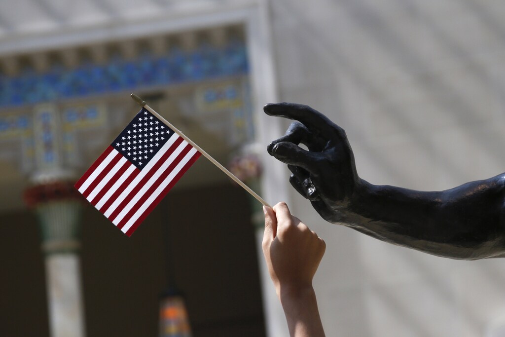 A girl holds a U.S. flag next to a sculpture after a naturalization ceremony at The Metropolitan Museum of Art in New York July 22, 2014. Seventy-five people from 42 countries became American citizens at an event held by U.S. Citizenship and Immigration Services (USCIS) at the Museum. REUTERS/Shannon Stapleton (UNITED STATES - Tags: SOCIETY POLITICS IMMIGRATION) - GM1EA7N03K501