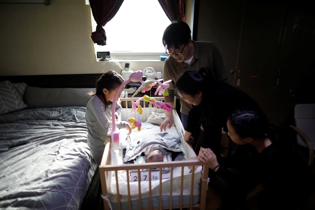 A family gathers around a new baby in a crib in Seoul, South Korea