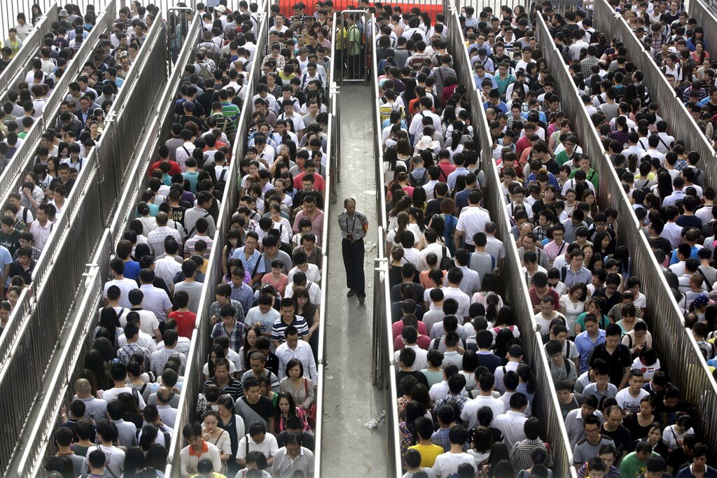 A security officer stands guard as passengers line up and wait for a security check during morning rush hour at Tiantongyuan North Station in Beijing May 27, 2014. Beijing tightened security checks at subway stations since last Saturday, following an attack in China's troubled Xinjiang region which killed 31 people on May 22, the deadliest act of violence in the region in years. REUTERS/Jason Lee (CHINA - Tags: CIVIL UNREST CRIME LAW TPX IMAGES OF THE DAY TRANSPORT) - GM1EA5R0S1D01