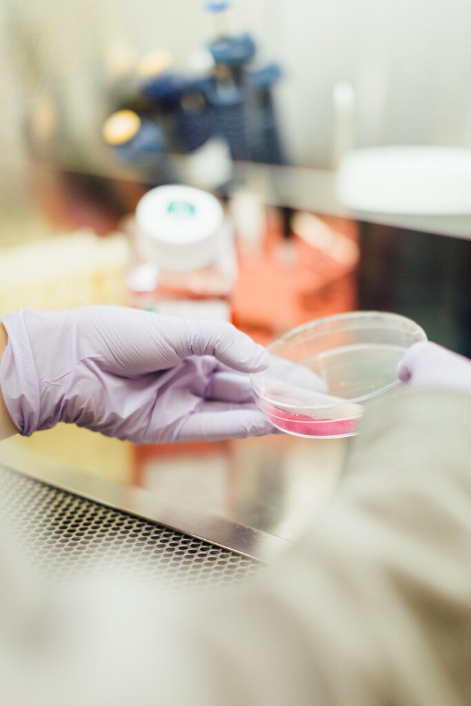 scientist wearing gloves handles a sample in a petri-dish